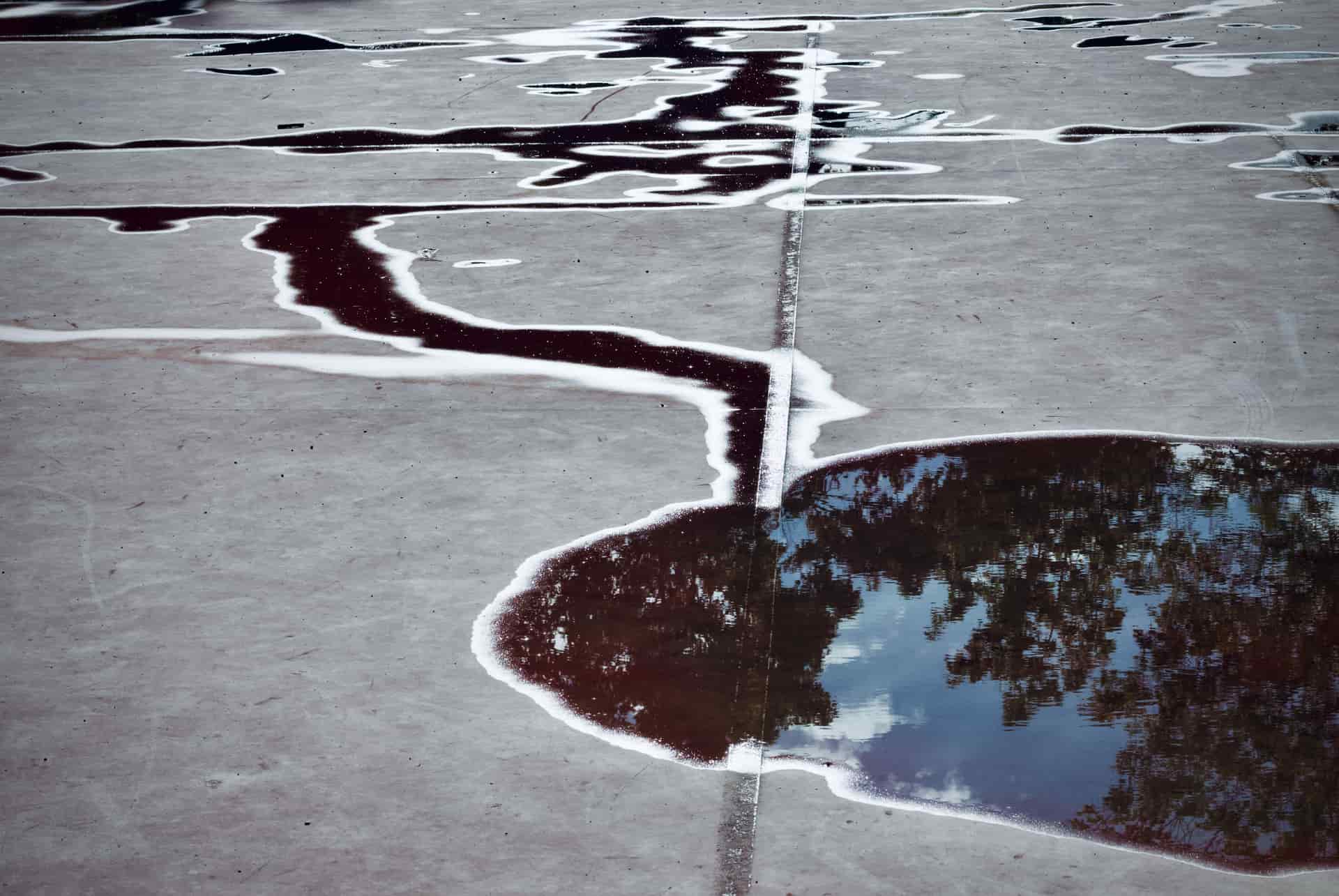A shallow puddle of water on a bare concrete floor