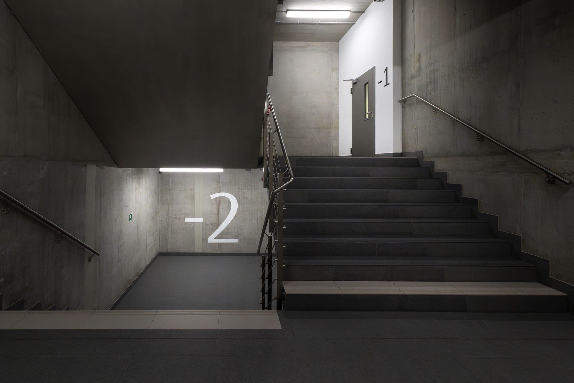 Concrete basement stairs descending into a dim below-grade room